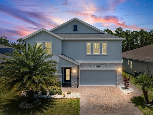 2452 Camden Park Ave, Davenport, FL 33837 - view of front of home with stucco siding, stone siding, decorative driveway, an attached garage, and roof with shingles