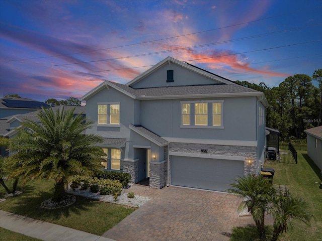 2452 Camden Park Ave, Davenport, FL 33837 - view of front of house with stucco siding, stone siding, decorative driveway, and an attached garage