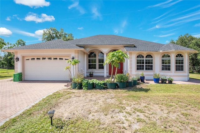 18852 Starry St, Orlando, FL 32833 - ranch-style house featuring an attached garage, decorative driveway, a front yard, roof with shingles, and stucco siding