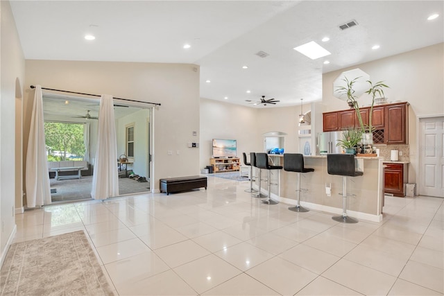 18852 Starry St, Orlando, FL 32833 - kitchen with a ceiling fan, stainless steel fridge, light tile patterned floors, high vaulted ceiling, and a breakfast bar area