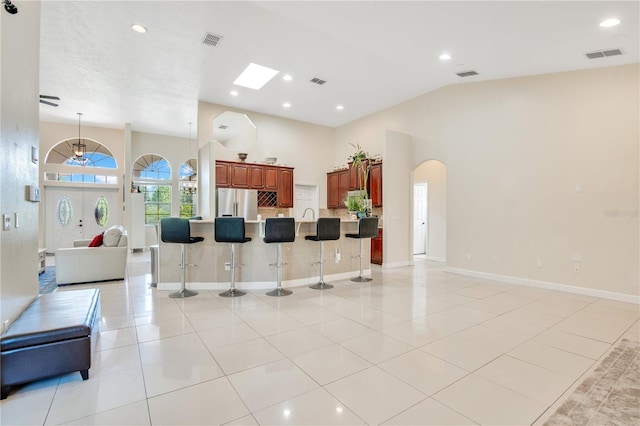 18852 Starry St, Orlando, FL 32833 - kitchen featuring open floor plan, freestanding refrigerator, a kitchen bar, arched walkways, and light tile patterned floors