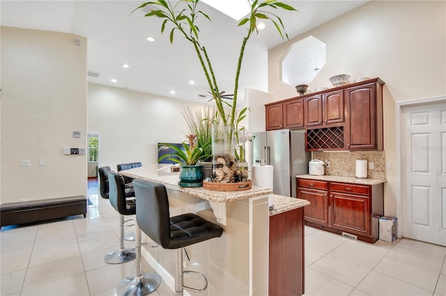 18852 Starry St, Orlando, FL 32833 - kitchen featuring stainless steel refrigerator with ice dispenser, light stone countertops, a kitchen bar, tasteful backsplash, and light tile patterned floors