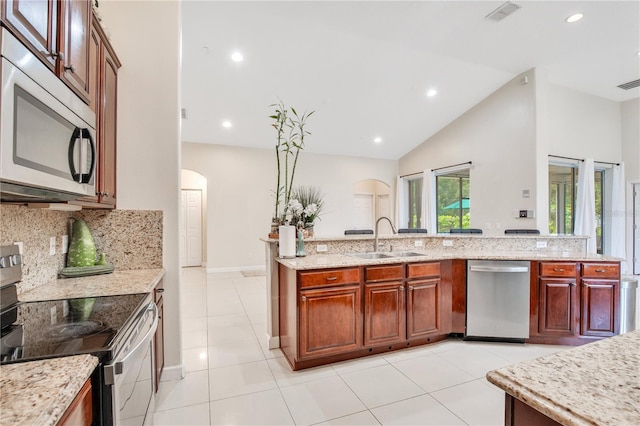 18852 Starry St, Orlando, FL 32833 - kitchen featuring appliances with stainless steel finishes, arched walkways, tasteful backsplash, light stone counters, and light tile patterned flooring