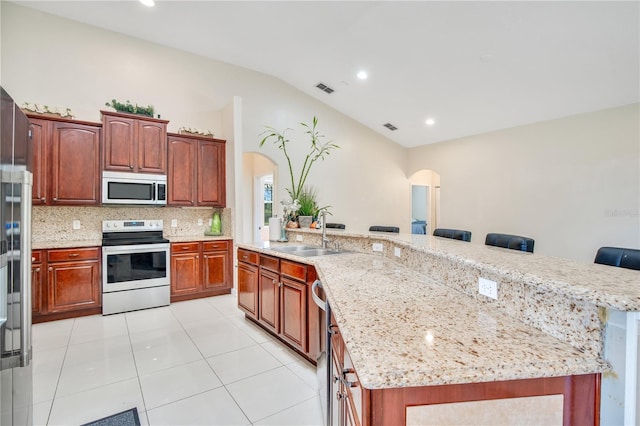 18852 Starry St, Orlando, FL 32833 - kitchen with stainless steel microwave, white range with electric stovetop, arched walkways, lofted ceiling, and decorative backsplash