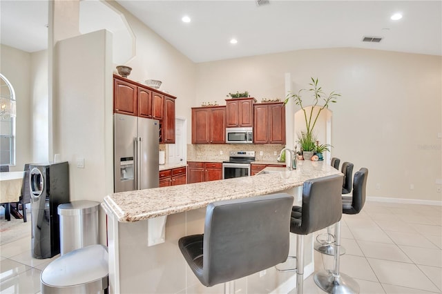 18852 Starry St, Orlando, FL 32833 - kitchen featuring appliances with stainless steel finishes, a breakfast bar, light tile patterned floors, backsplash, and recessed lighting