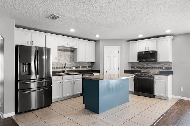 2885 Lafayette Trace Dr, Saint Cloud, FL 34772 - kitchen featuring appliances with stainless steel finishes, white cabinetry, tasteful backsplash, a kitchen island, and dark countertops