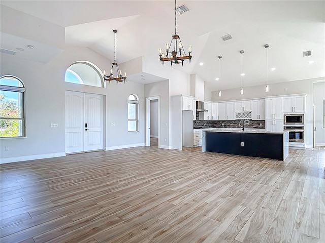 1329 Jumana Loop, Apollo Beach, FL 33572 - kitchen with appliances with stainless steel finishes, a chandelier, open floor plan, light wood-type flooring, and high vaulted ceiling
