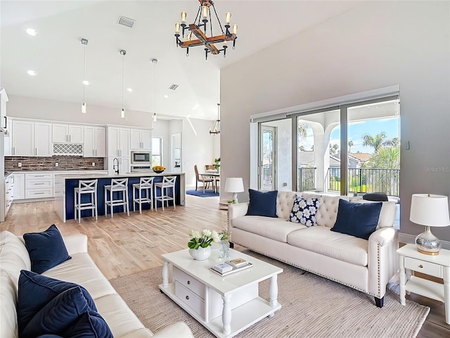 1329 Jumana Loop, Apollo Beach, FL 33572 - living area featuring a chandelier, light wood-style floors, a towering ceiling, and recessed lighting