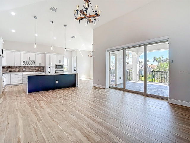 1329 Jumana Loop, Apollo Beach, FL 33572 - unfurnished living room with a chandelier, a towering ceiling, light wood-style floors, and recessed lighting