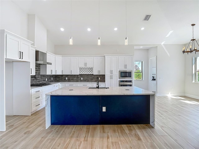 1329 Jumana Loop, Apollo Beach, FL 33572 - kitchen featuring wall chimney range hood, stainless steel appliances, decorative backsplash, light wood finished floors, and white cabinets