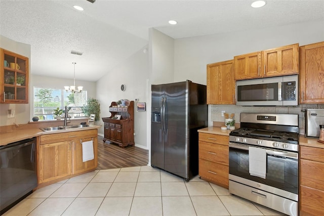2212 Clementine Trl, Clermont, FL 34714 - kitchen with stainless steel appliances, a chandelier, light countertops, vaulted ceiling, and glass insert cabinets