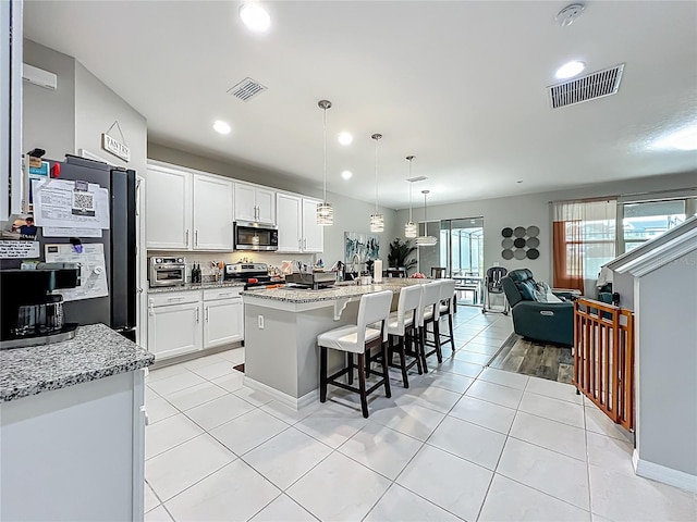 1808 Regal River Cir, Ocoee, FL 34761 - kitchen with appliances with stainless steel finishes, recessed lighting, light tile patterned floors, a breakfast bar, and white cabinetry