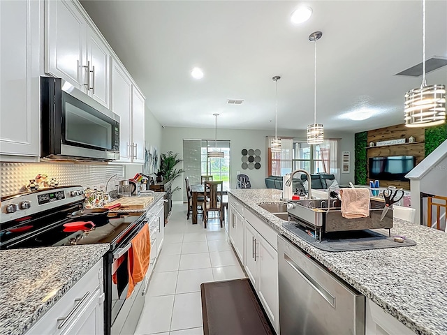 1808 Regal River Cir, Ocoee, FL 34761 - kitchen featuring stainless steel appliances, light tile patterned flooring, hanging light fixtures, white cabinets, and light stone counters