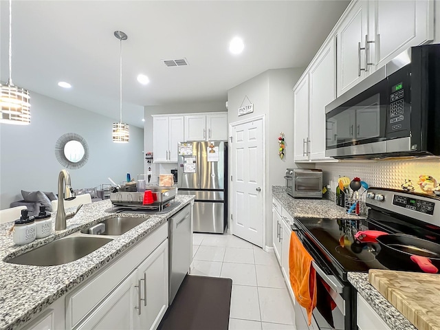 1808 Regal River Cir, Ocoee, FL 34761 - kitchen with stainless steel appliances, light tile patterned floors, white cabinetry, decorative light fixtures, and recessed lighting