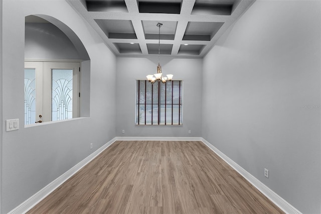 2495 Squaw Crk, Clermont, FL 34711 - empty room featuring wood finished floors, beam ceiling, coffered ceiling, arched walkways, and a chandelier