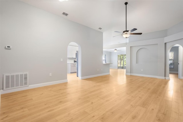 988 Vanderbilt Dr, Eustis, FL 32726 - unfurnished living room with arched walkways, a ceiling fan, high vaulted ceiling, healthy amount of natural light, and light wood-type flooring