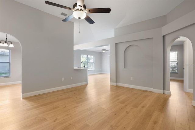 988 Vanderbilt Dr, Eustis, FL 32726 - spare room featuring arched walkways, ceiling fan, high vaulted ceiling, light wood finished floors, and a chandelier