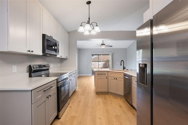 988 Vanderbilt Dr, Eustis, FL 32726 - kitchen with appliances with stainless steel finishes, a peninsula, light countertops, light wood finished floors, and ceiling fan