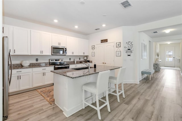 16400 Winding Preserve Cir, Clermont, FL 34714 - kitchen with appliances with stainless steel finishes, light wood finished floors, white cabinetry, a breakfast bar area, and recessed lighting
