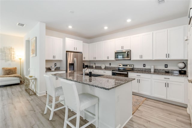 16400 Winding Preserve Cir, Clermont, FL 34714 - kitchen featuring stainless steel appliances, light wood finished floors, a breakfast bar area, dark stone countertops, and recessed lighting
