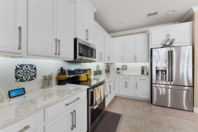 1208 Fieldstone Cir, Oviedo, FL 32765 - kitchen with stainless steel appliances, light tile patterned floors, white cabinets, light stone counters, and tasteful backsplash