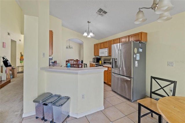 1305 Rebecca Dr, Haines City, FL 33844 - kitchen with appliances with stainless steel finishes, a chandelier, arched walkways, light tile patterned floors, and brown cabinetry
