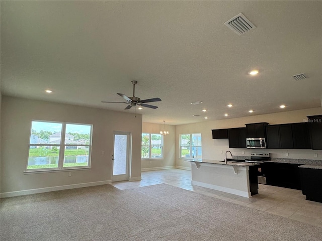 4101 Sagefield Dr, Harmony, FL 34773 - kitchen featuring stainless steel appliances, dark cabinets, open floor plan, recessed lighting, and a kitchen breakfast bar