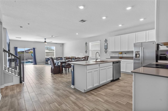 4491 Holstein St, Saint Cloud, FL 34772 - kitchen with appliances with stainless steel finishes, a textured ceiling, an island with sink, white cabinets, and ceiling fan