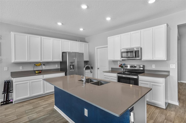 4491 Holstein St, Saint Cloud, FL 34772 - kitchen with stainless steel appliances, light wood-type flooring, white cabinets, a kitchen island with sink, and recessed lighting
