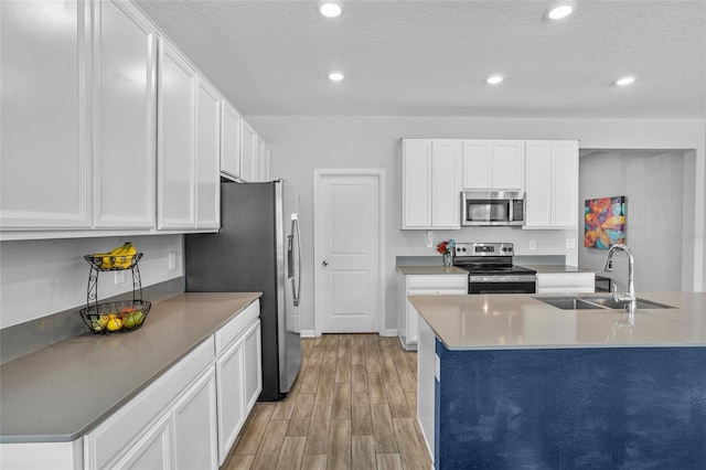 4491 Holstein St, Saint Cloud, FL 34772 - kitchen featuring stainless steel appliances, light wood-style floors, white cabinetry, recessed lighting, and a textured ceiling