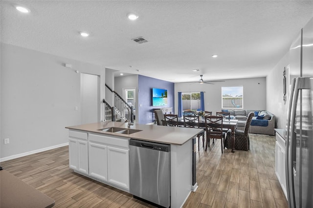 4491 Holstein St, Saint Cloud, FL 34772 - kitchen with appliances with stainless steel finishes, open floor plan, light wood-style flooring, white cabinets, and a ceiling fan