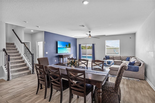 4491 Holstein St, Saint Cloud, FL 34772 - dining space with light wood finished floors, stairway, a ceiling fan, and a textured ceiling