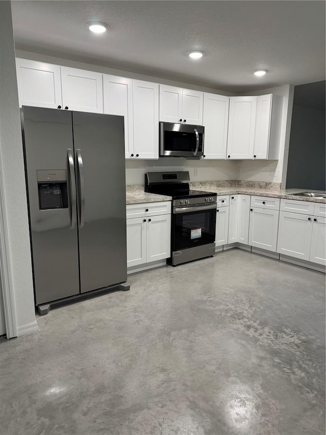 120 Highland Ave, Auburndale, FL 33823 - kitchen featuring appliances with stainless steel finishes, white cabinetry, finished concrete flooring, recessed lighting, and light stone countertops