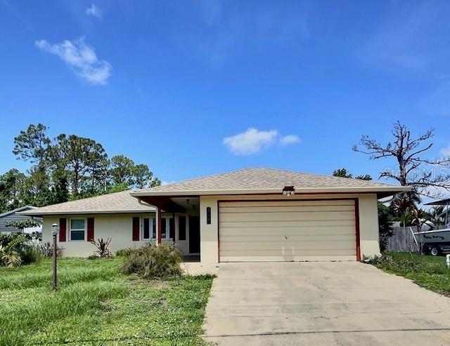 520 Jupiter Blvd NW, Palm Bay, FL 32907 - ranch-style home with stucco siding, driveway, an attached garage, and a front yard