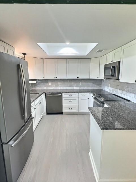 520 Jupiter Blvd NW, Palm Bay, FL 32907 - kitchen featuring stainless steel appliances, white cabinetry, tasteful backsplash, and light wood finished floors