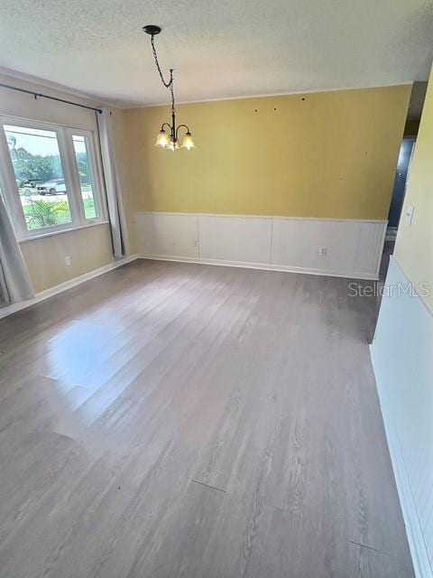 520 Jupiter Blvd NW, Palm Bay, FL 32907 - unfurnished room featuring a chandelier, wood finished floors, wainscoting, and a textured ceiling
