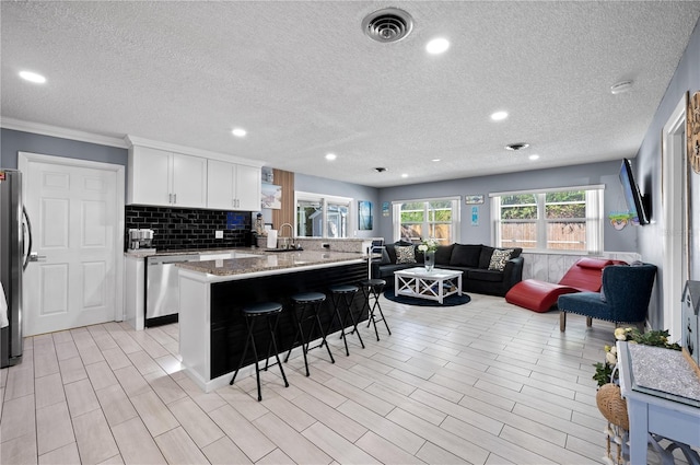 874 Acadia Rd, Venice, FL 34293 - kitchen with appliances with stainless steel finishes, open floor plan, a breakfast bar area, a textured ceiling, and a peninsula