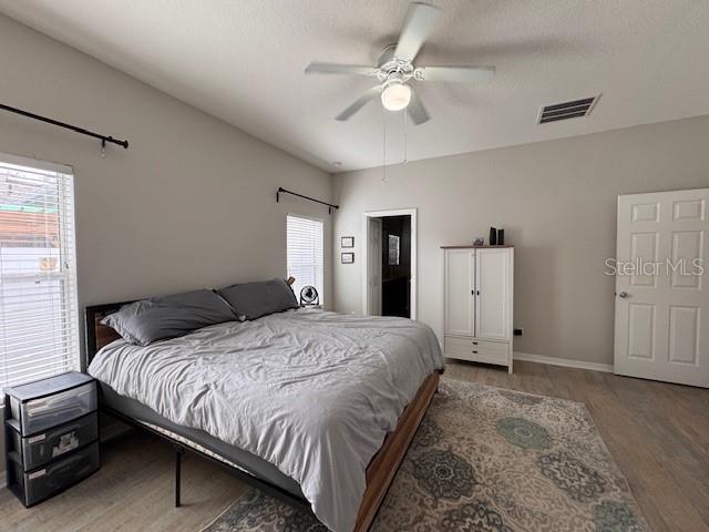 14548 Black Cherry Trl, Winter Garden, FL 34787 - bedroom with wood finished floors, multiple windows, and ceiling fan