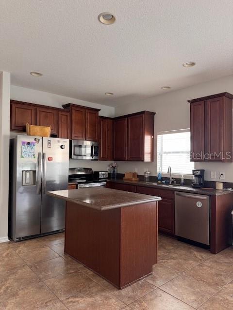 14548 Black Cherry Trl, Winter Garden, FL 34787 - kitchen featuring appliances with stainless steel finishes, dark countertops, a kitchen island, recessed lighting, and light tile patterned flooring