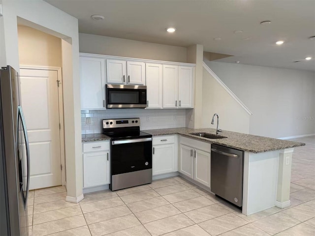 2602 Buena View Rd, Kissimmee, FL 34746 - kitchen featuring appliances with stainless steel finishes, a peninsula, white cabinets, tasteful backsplash, and dark stone counters