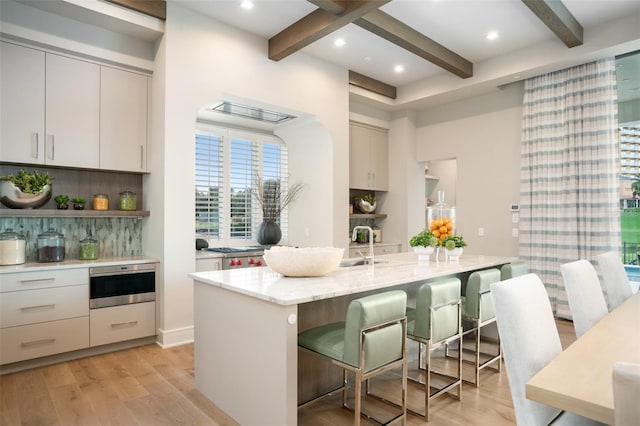 4162 Grande Brick Loop Unit 27, Orlando, FL 32837 - kitchen with light wood-style floors, beamed ceiling, backsplash, a kitchen breakfast bar, and light stone counters