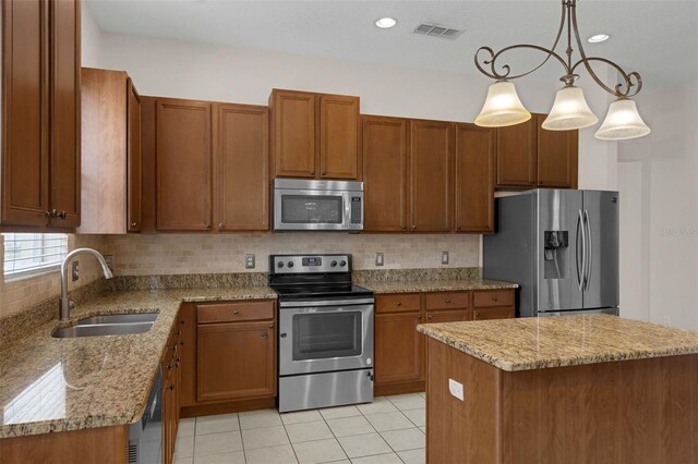 2534 Double Tree Pl, Oviedo, FL 32766 - kitchen featuring appliances with stainless steel finishes, brown cabinetry, light stone counters, light tile patterned floors, and decorative backsplash