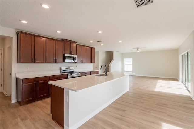 3840 Fescue St, Clermont, FL 34714 - kitchen with appliances with stainless steel finishes, light wood-type flooring, a kitchen island with sink, ceiling fan, and light countertops