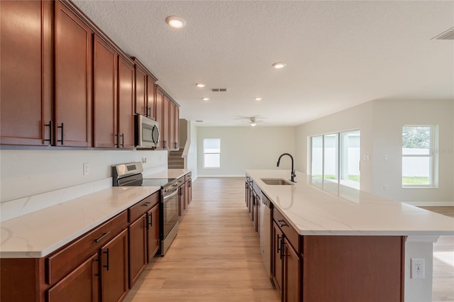 3840 Fescue St, Clermont, FL 34714 - kitchen featuring appliances with stainless steel finishes, light wood finished floors, recessed lighting, a large island with sink, and a ceiling fan