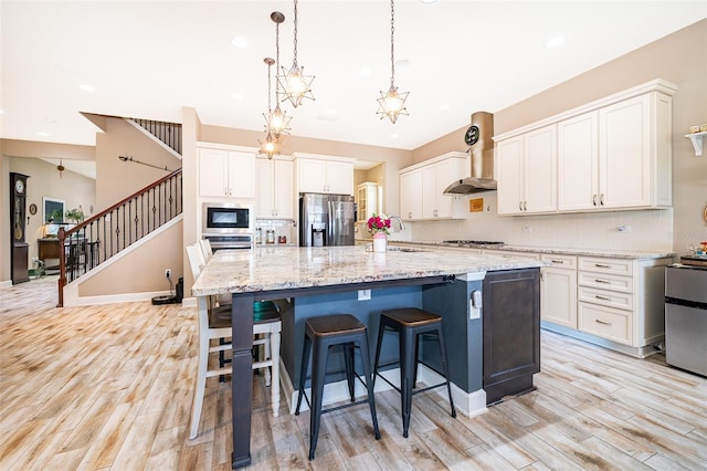 3546 Mediterra Dr, Clermont, FL 34711 - kitchen with appliances with stainless steel finishes, light wood-style flooring, recessed lighting, decorative backsplash, and wall chimney exhaust hood