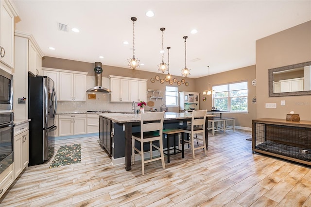 3546 Mediterra Dr, Clermont, FL 34711 - kitchen featuring fridge with ice dispenser, light wood-style floors, a center island with sink, a kitchen breakfast bar, and decorative backsplash