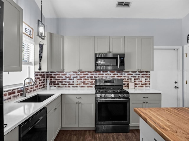 15718 Carriage Hill Ct, Clermont, FL 34711 - kitchen featuring appliances with stainless steel finishes, butcher block countertops, dark wood finished floors, hanging light fixtures, and gray cabinetry