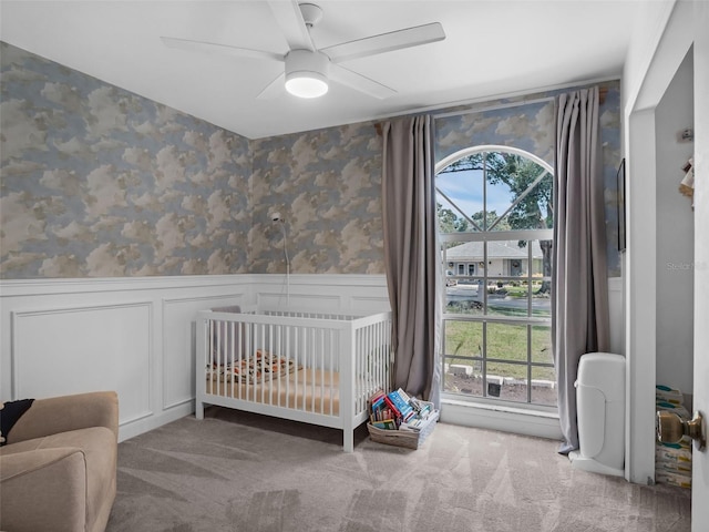 15718 Carriage Hill Ct, Clermont, FL 34711 - carpeted bedroom featuring a wainscoted wall, wallpapered walls, a crib, ceiling fan, and a decorative wall