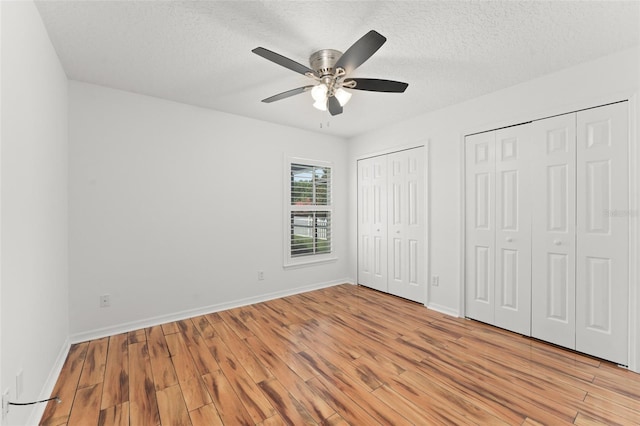 11341 Autumn Wind Loop, Clermont, FL 34711 - unfurnished bedroom with light wood-style floors, multiple closets, a textured ceiling, and ceiling fan