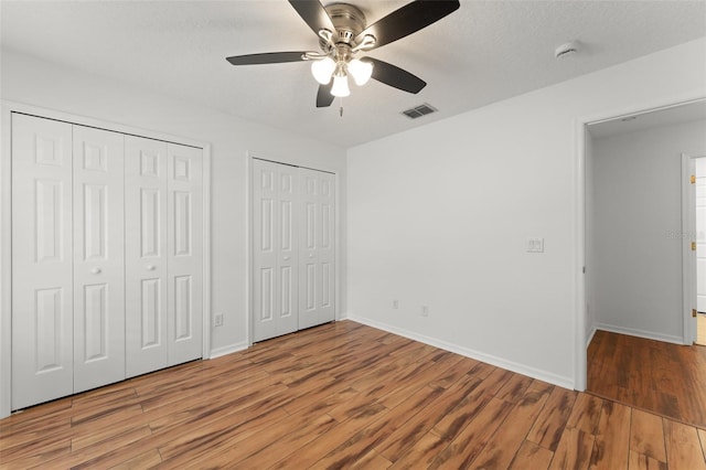 11341 Autumn Wind Loop, Clermont, FL 34711 - unfurnished bedroom featuring two closets, wood finished floors, and ceiling fan